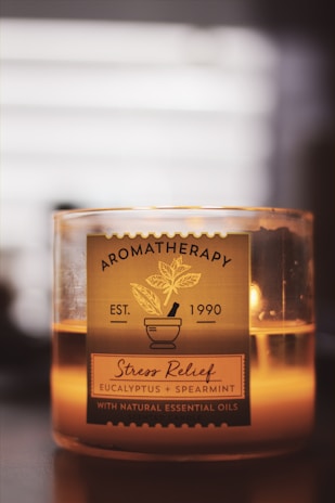 A candle labeled 'Aromatherapy Stress Relief' with eucalyptus and spearmint essential oils. The design includes a mortar and pestle illustration, creating a soothing and relaxing atmosphere.