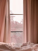 Cozy bedroom scene with a woman lounging in soft pajamas by a window.