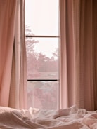 Bedroom with soft drapes framing a large window at dusk