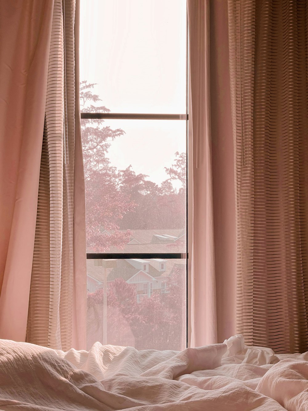 Weißer Fenstervorhang in der Nähe des weißen Bettes