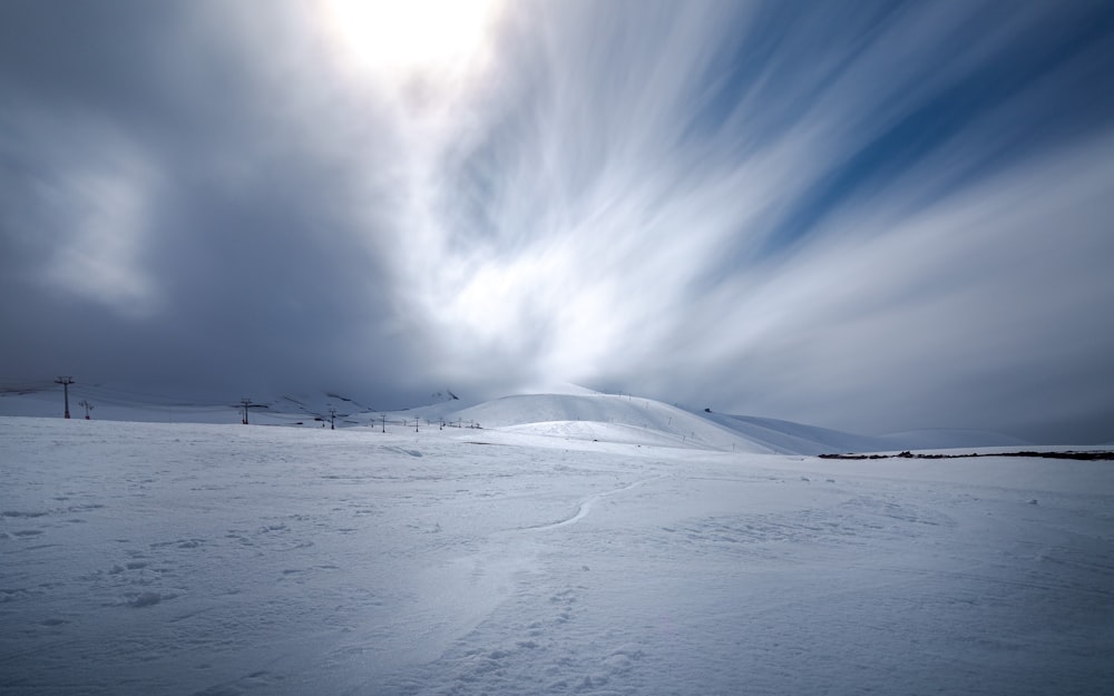 snow covered field under cloudy sky