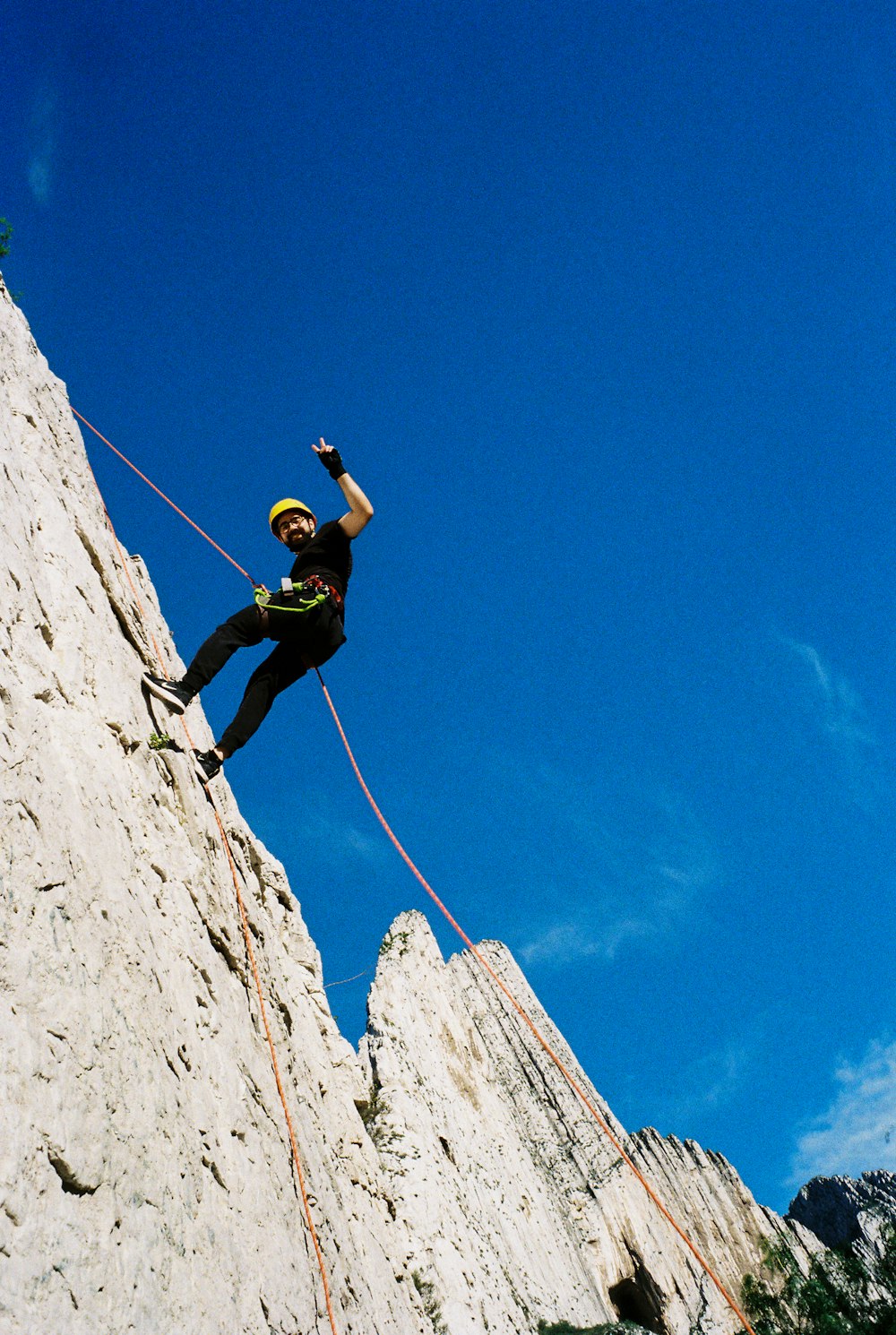 man in green shirt climbing on rocky mountain during daytime