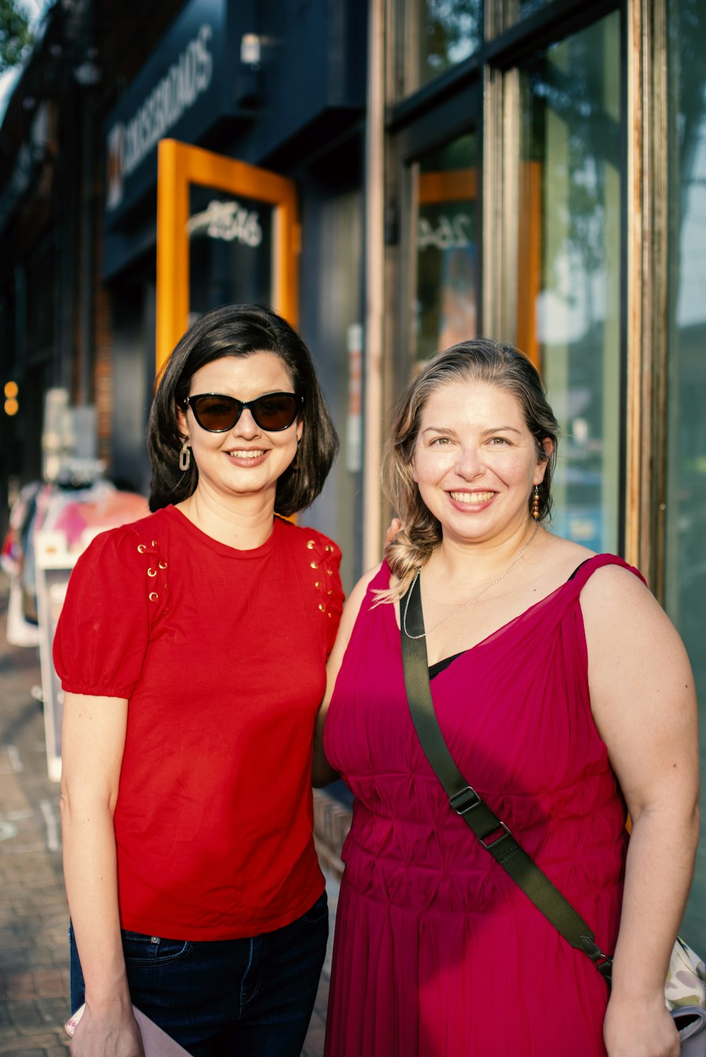 2 women smiling in front of brown wooden framed glass window