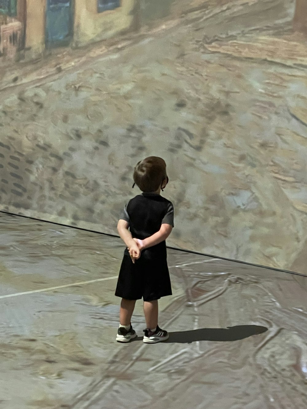 boy in black t-shirt and shorts standing on brown sand during daytime