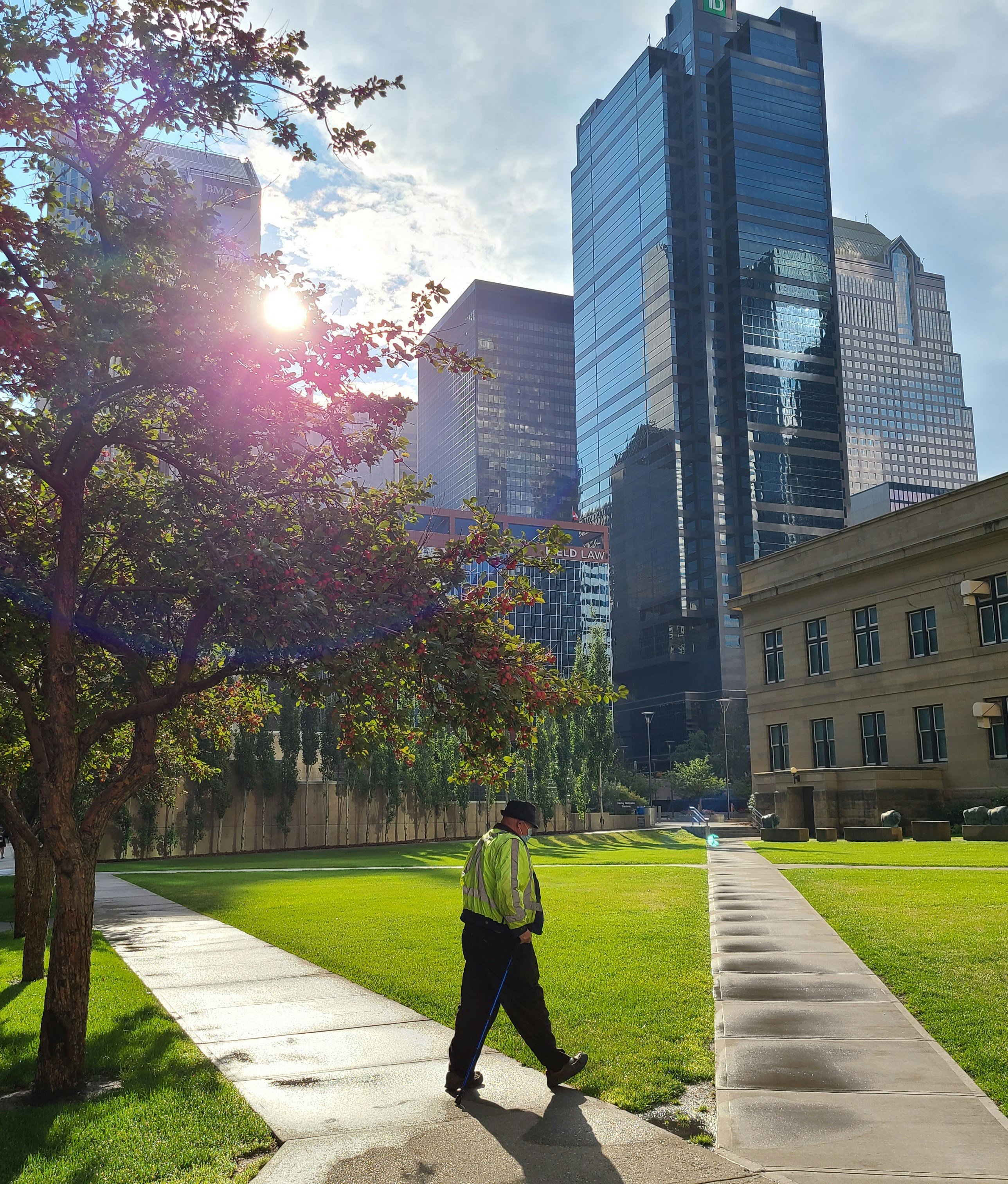 Man in green jacket walking on pathway near trees and building during ...