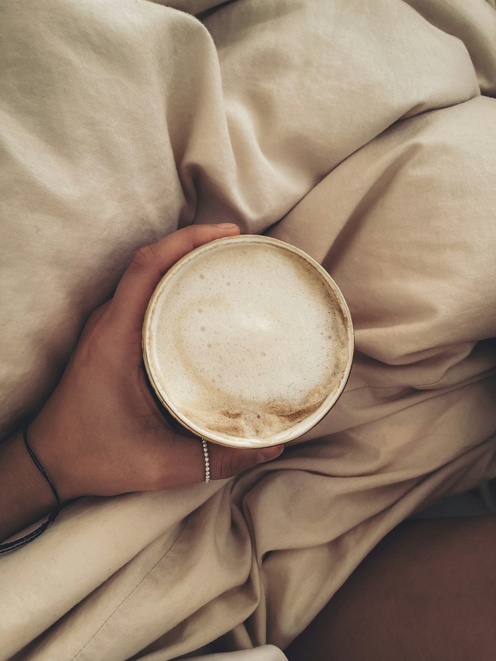 person holding white ceramic mug with brown liquid