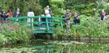 people sitting on green wooden bench near river during daytime
