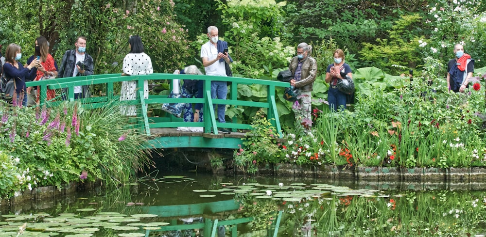 people sitting on green wooden bench near river during daytime