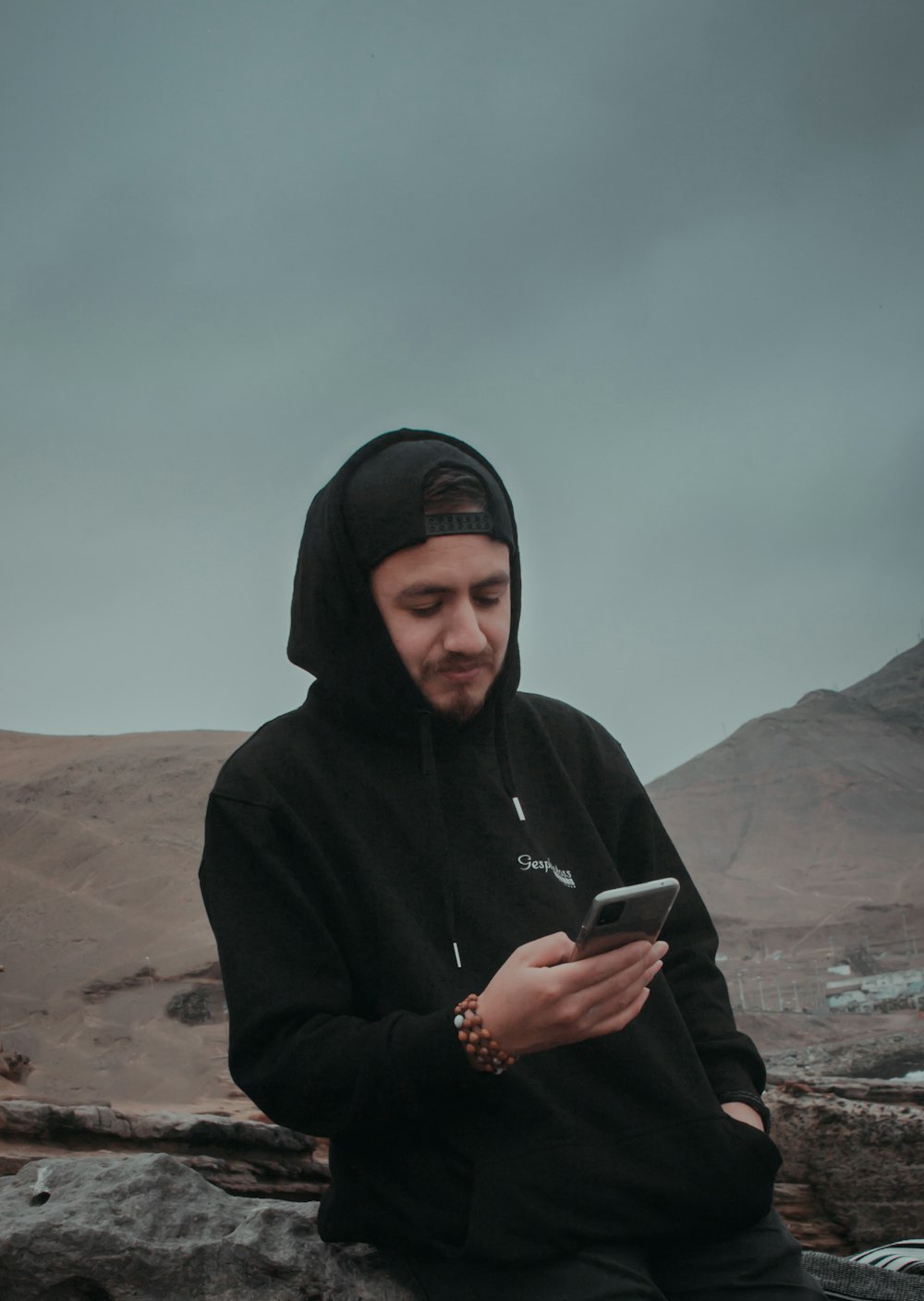 man in black hoodie holding smartphone