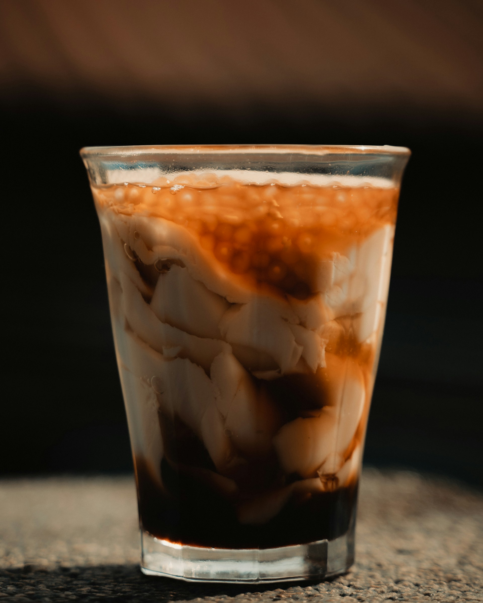 clear drinking glass with ice and brown liquid
