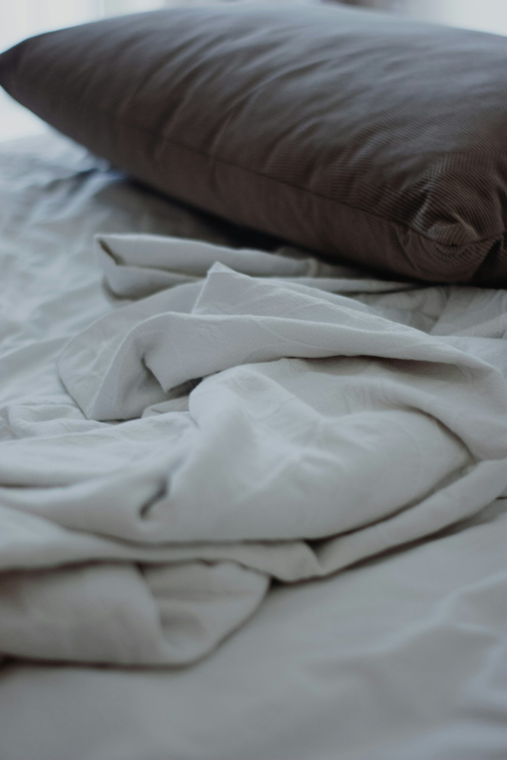 weißes Textil auf weißem Bett