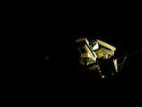 A pair of surveillance cameras is mounted on a pole, illuminated against a dark background. The cameras have rectangular shapes with distinct lenses and are positioned to cover different angles.