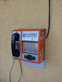 red and black telephone mounted on beige wall