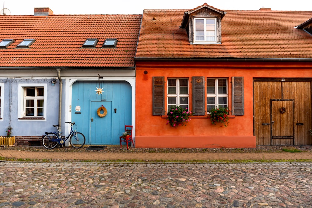 blue bicycle parked beside brown concrete building