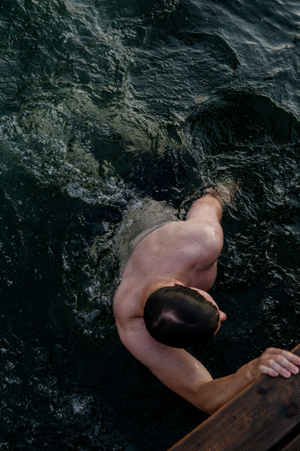 person swimming on body of water during daytime