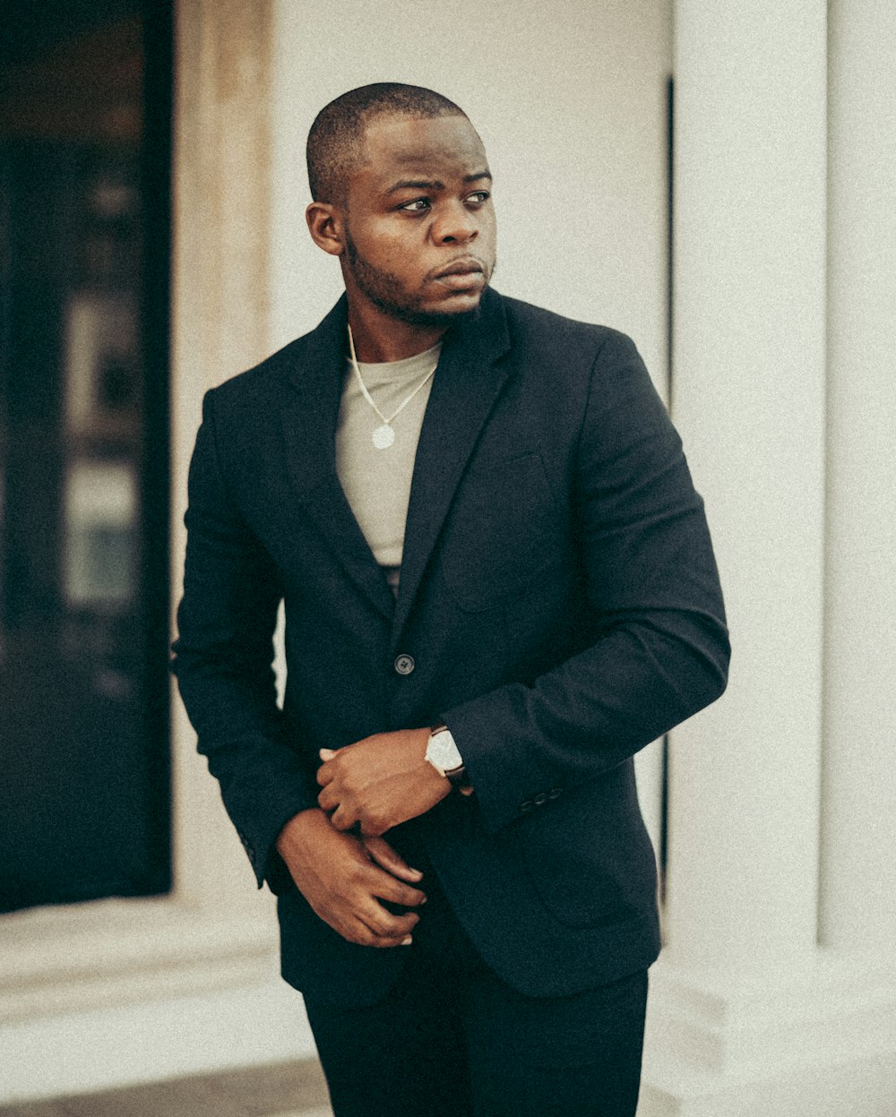 man in black suit jacket standing near white wall