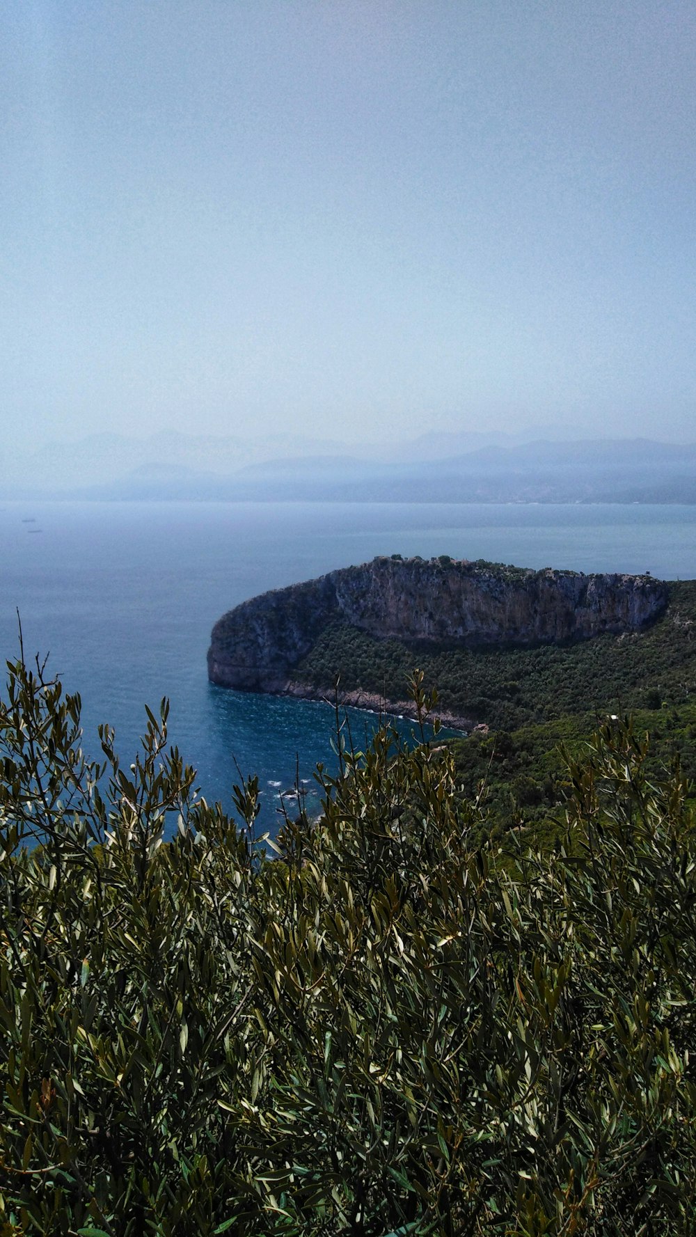 green mountain beside body of water during daytime