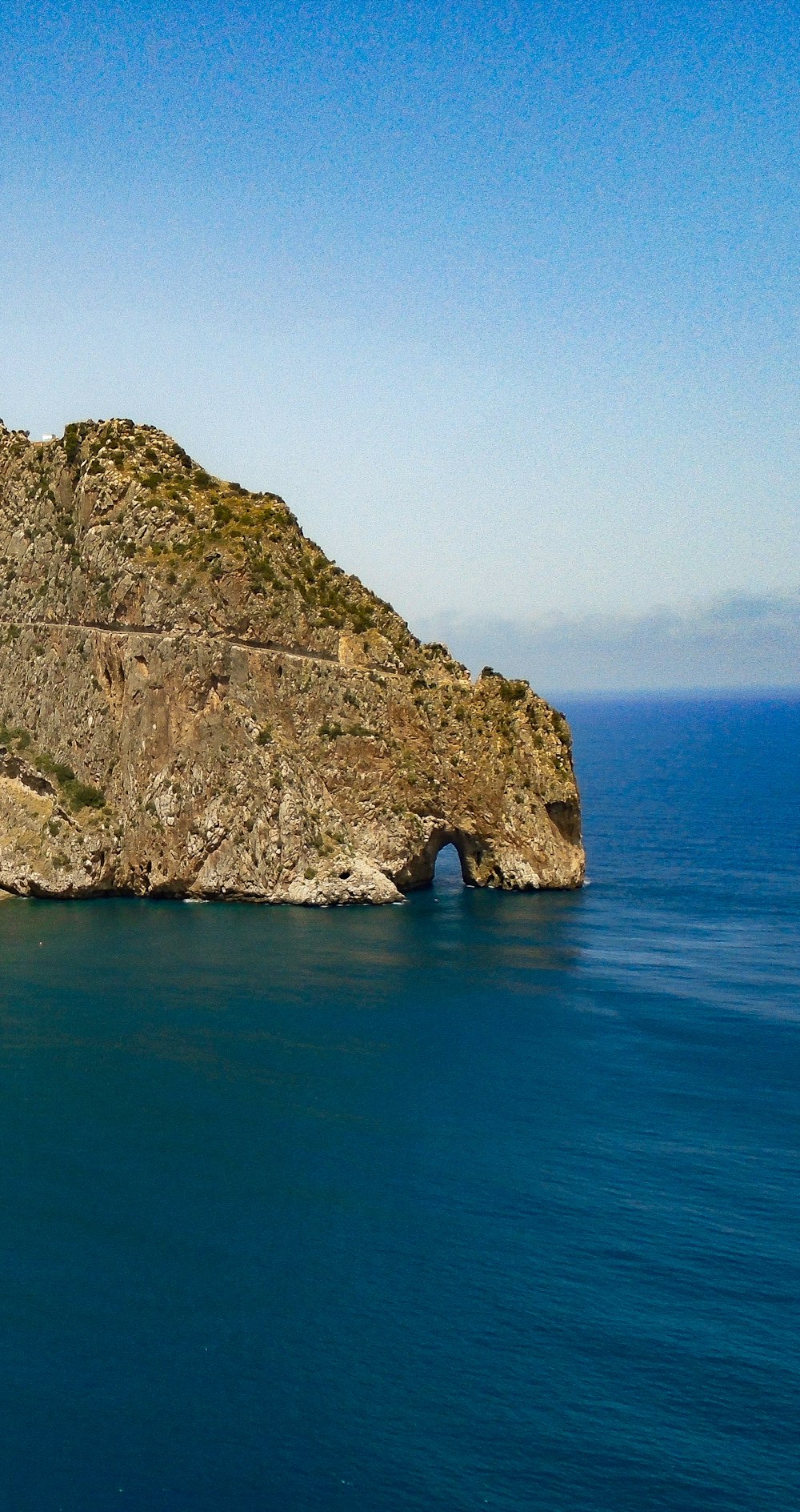 brown rock formation on blue sea under blue sky during daytime