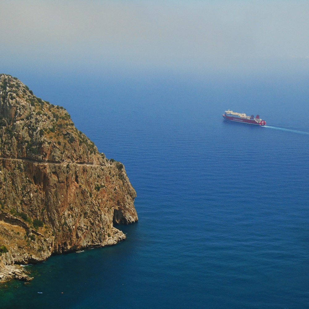 white boat on blue sea beside brown and green mountain during daytime