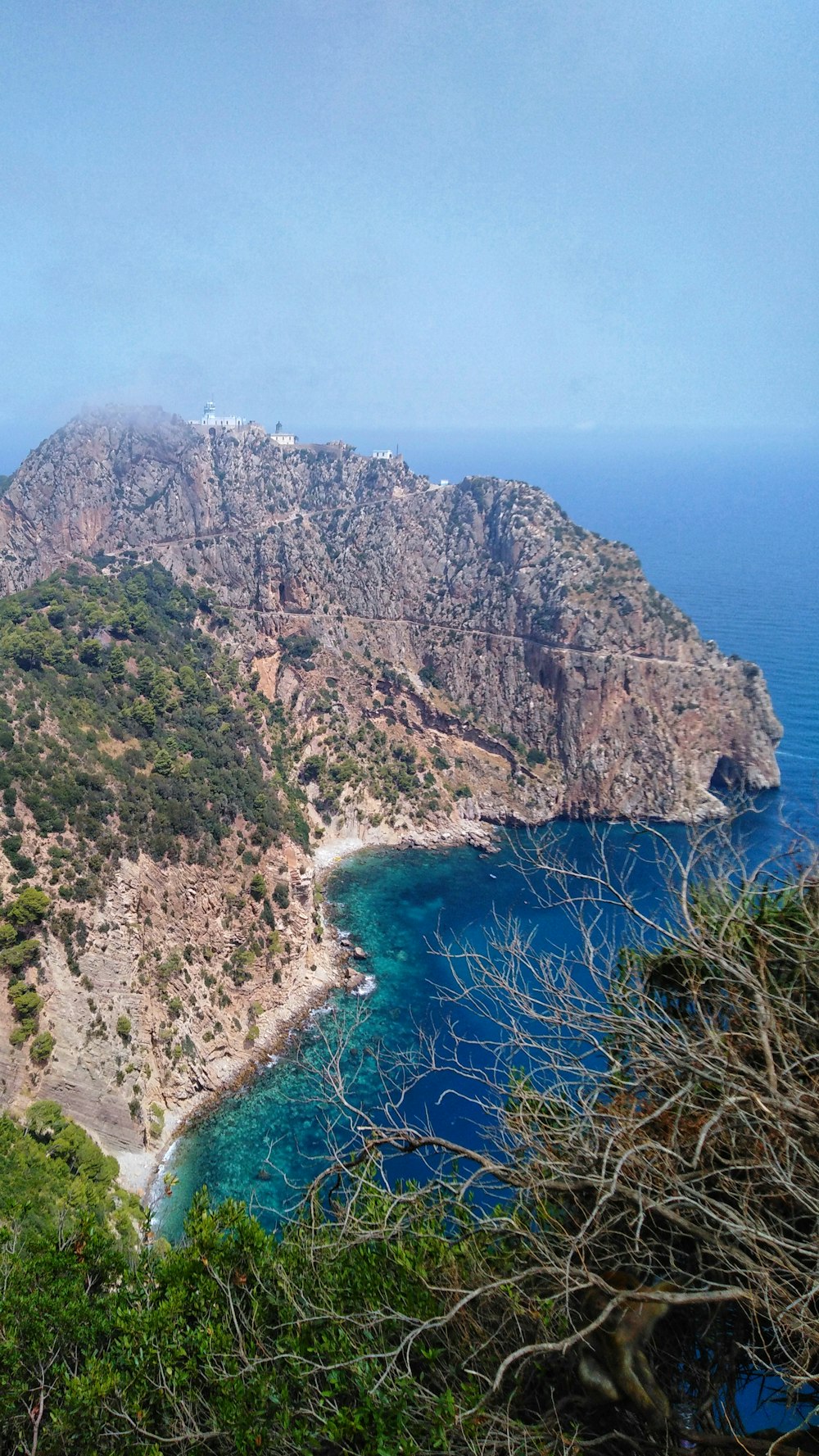 green and brown mountain beside blue sea during daytime