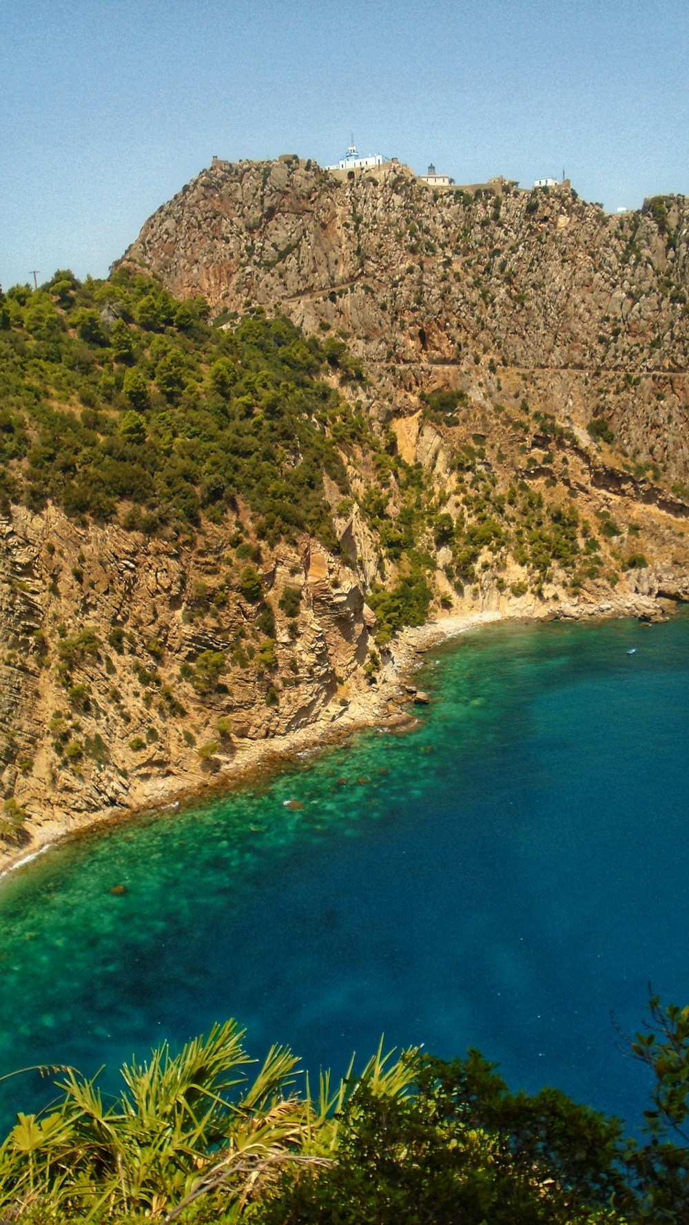 green and brown mountain beside blue body of water during daytime