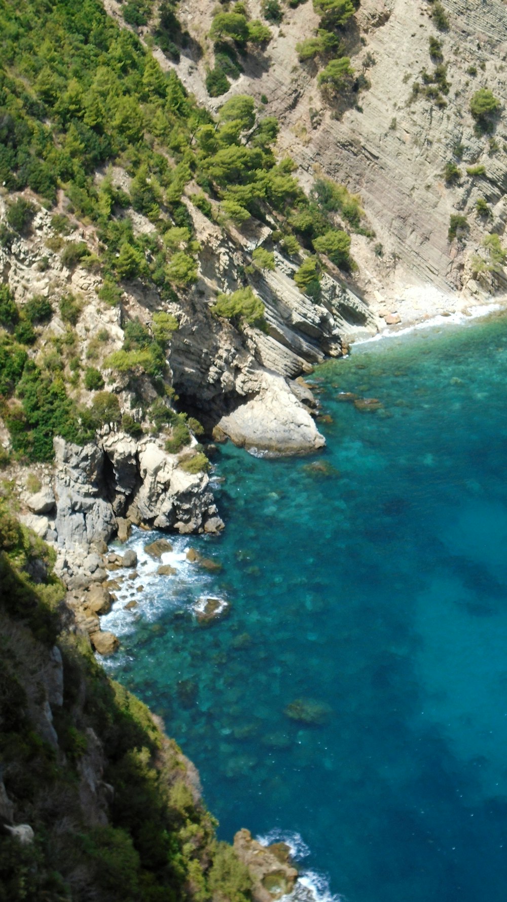 green and brown rocky mountain beside blue sea during daytime