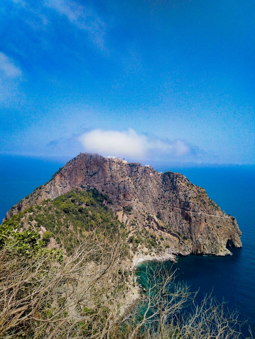green and brown mountain beside blue sea under blue sky during daytime