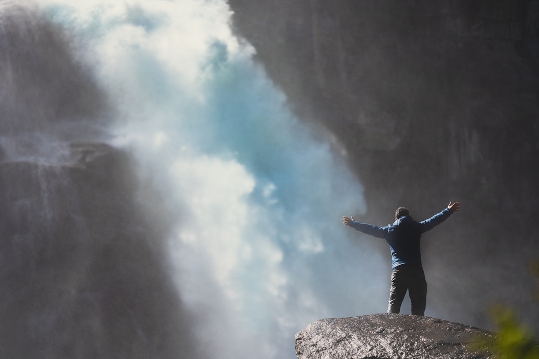 man in black jacket standing on brown rock mountain during daytime