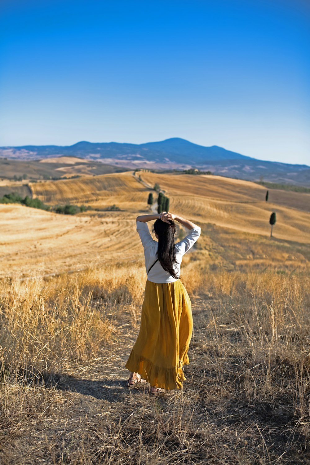 woman in yellow dress standing on brown grass field during daytime