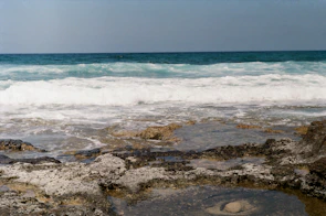 Close-up of crystal-clear ocean waves crashing against smooth rocks.