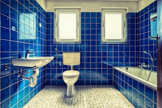 white ceramic sink beside blue wall tiles