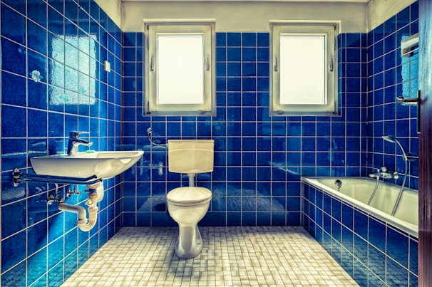 white ceramic sink beside blue wall tiles