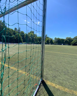 Outdoor futsal 5v5 field surrounded by green trees on a sunny day