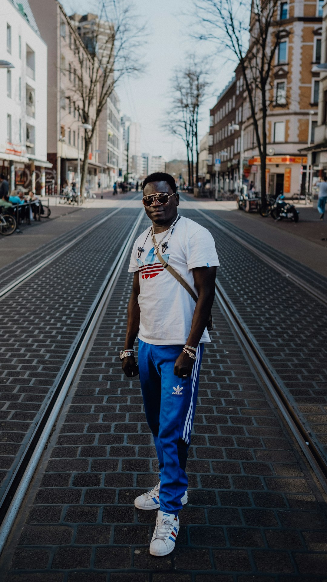 man in white crew neck t-shirt and blue pants standing on the road