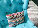 A colorful cushion placed on a modern chair, adding a pop of personality to the space.