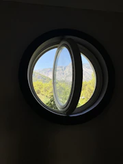 Large window view from Alpine Haven showing the rugged mountain terrain and forest green valleys.