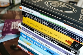 stack of books on brown wooden table