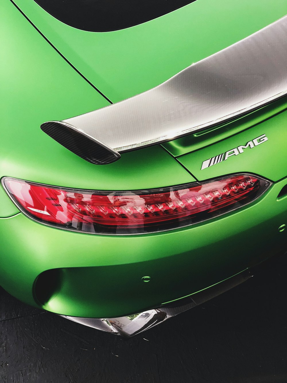 Porsche 911 verte garée sur une chaussée grise
