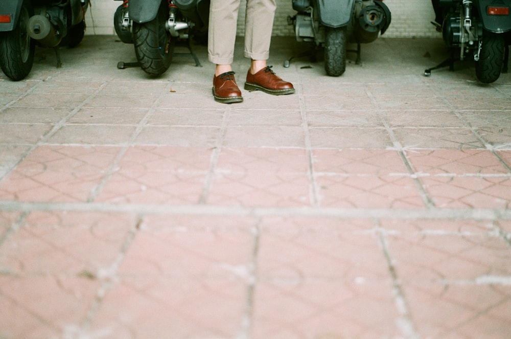 person in white pants and brown leather shoes