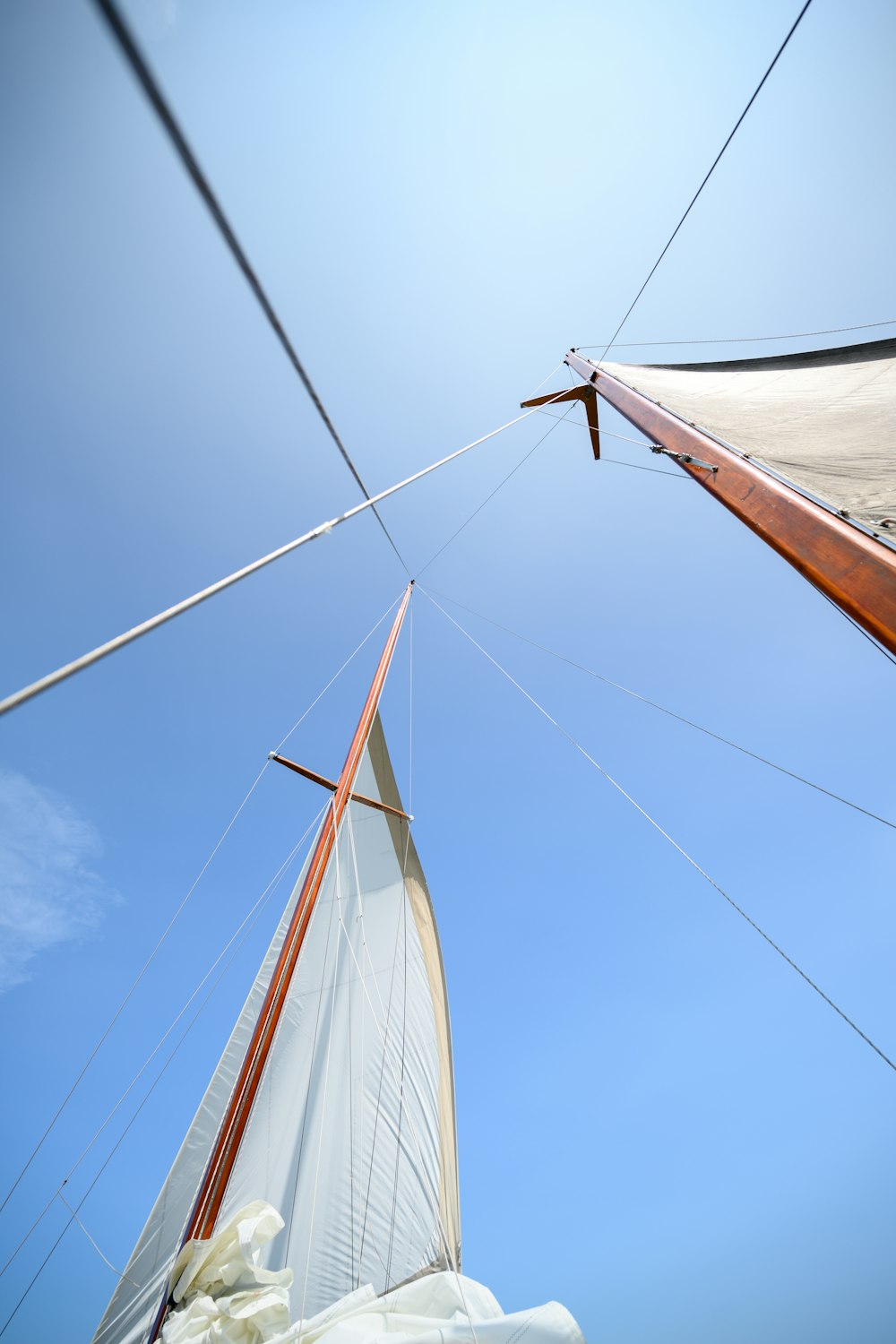 brown and white sail boat on water under blue sky during daytime