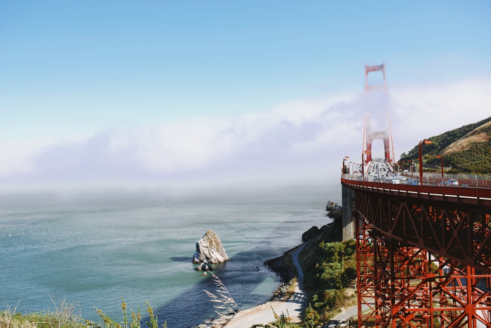 red and white tower on top of brown rock formation near body of water during daytime