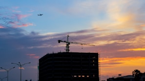 Crane lifting heavy materials at a busy construction area during sunset.