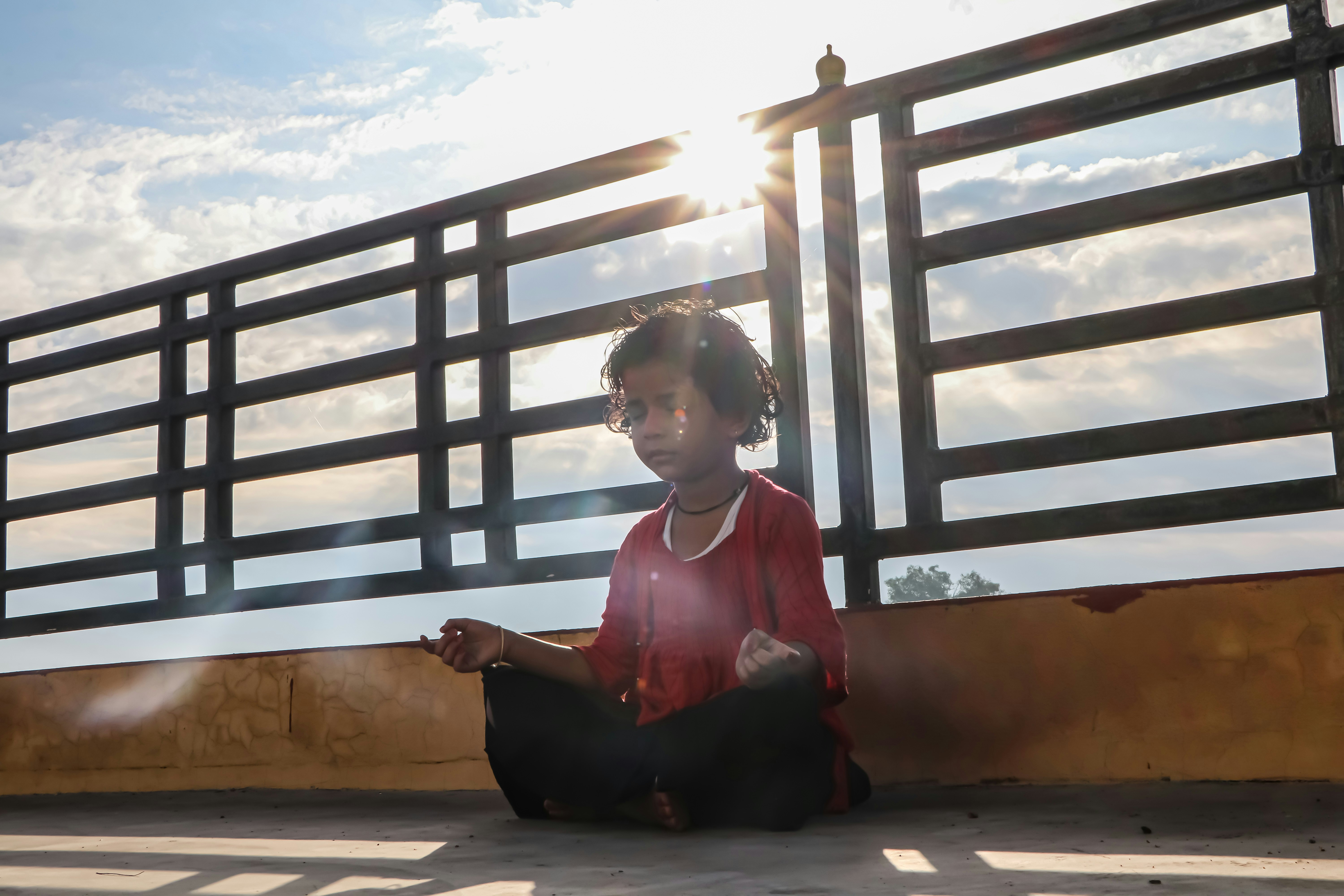 Woman in red long sleeve shirt sitting on brown wooden stairs during daytime