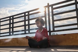 woman in red long sleeve shirt sitting on brown wooden stairs during daytime