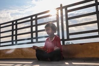 woman in red long sleeve shirt sitting on brown wooden stairs during daytime