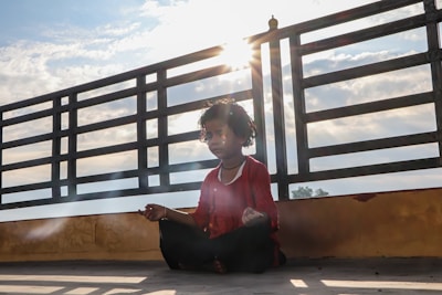 woman in red long sleeve shirt sitting on brown wooden stairs during daytime