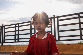 A young child with eyes closed, hands folded, surrounded by gentle island scenery and soft glowing light.