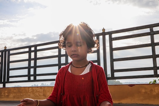 A young child with eyes closed, hands folded, surrounded by gentle island scenery and soft glowing light.