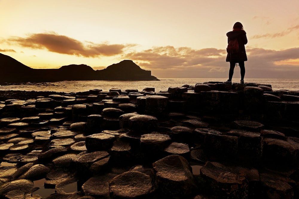 man standing on rocky shore during daytime