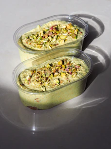 Close-up of creamy pistachio ice cream in a matte forest green cup, softly lit by natural light.